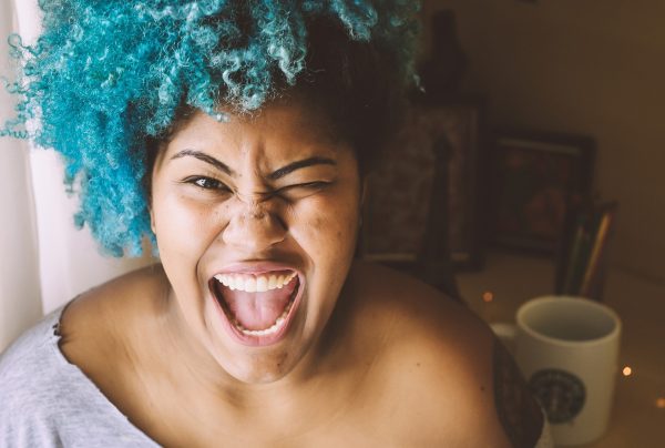 Very happy woman with curly blue hair.